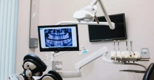Modern dental operatory featuring a panoramic dental x-ray displayed on a monitor, with overhead lighting and dental tools ready for use.