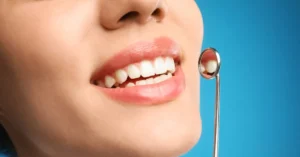 Close-up of a smiling woman’s mouth with a dental mirror reflecting clean white teeth, symbolizing oral health and preventive dental care.