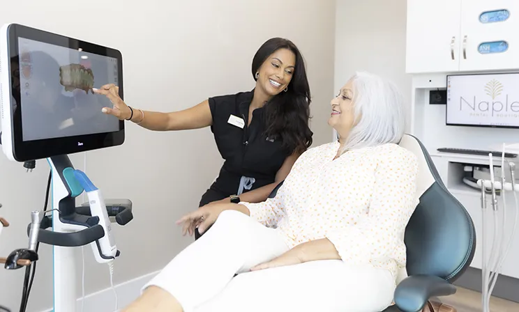 Dr. Hemita klose showing a 3d dental scan to a patient during a consultation at naples dental boutique.