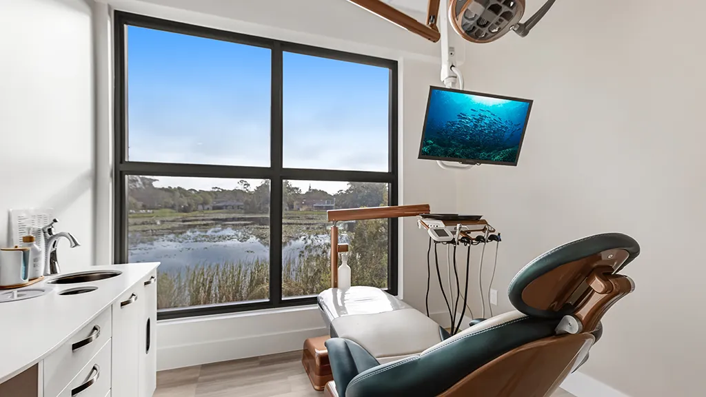 Modern dental treatment room at naples dental boutique featuring a relaxing lake view and state-of-the-art equipment.