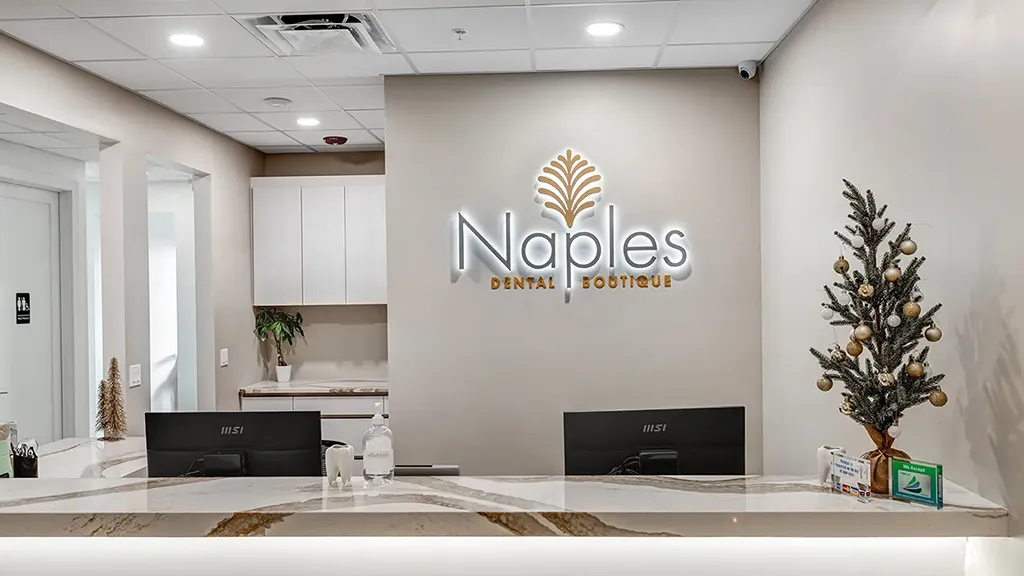 Front desk and illuminated logo wall at naples dental boutique in naples, florida.