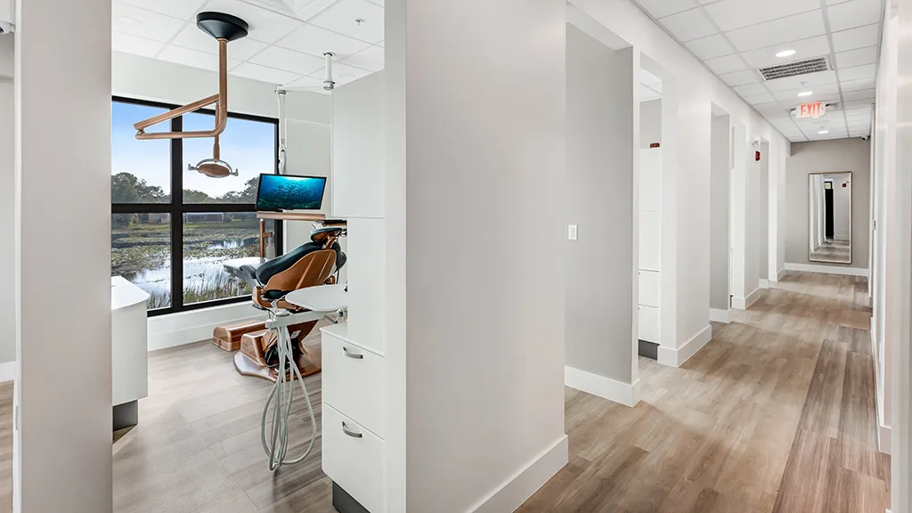 Modern dental treatment room with lake view and bright hallway at naples dental boutique.